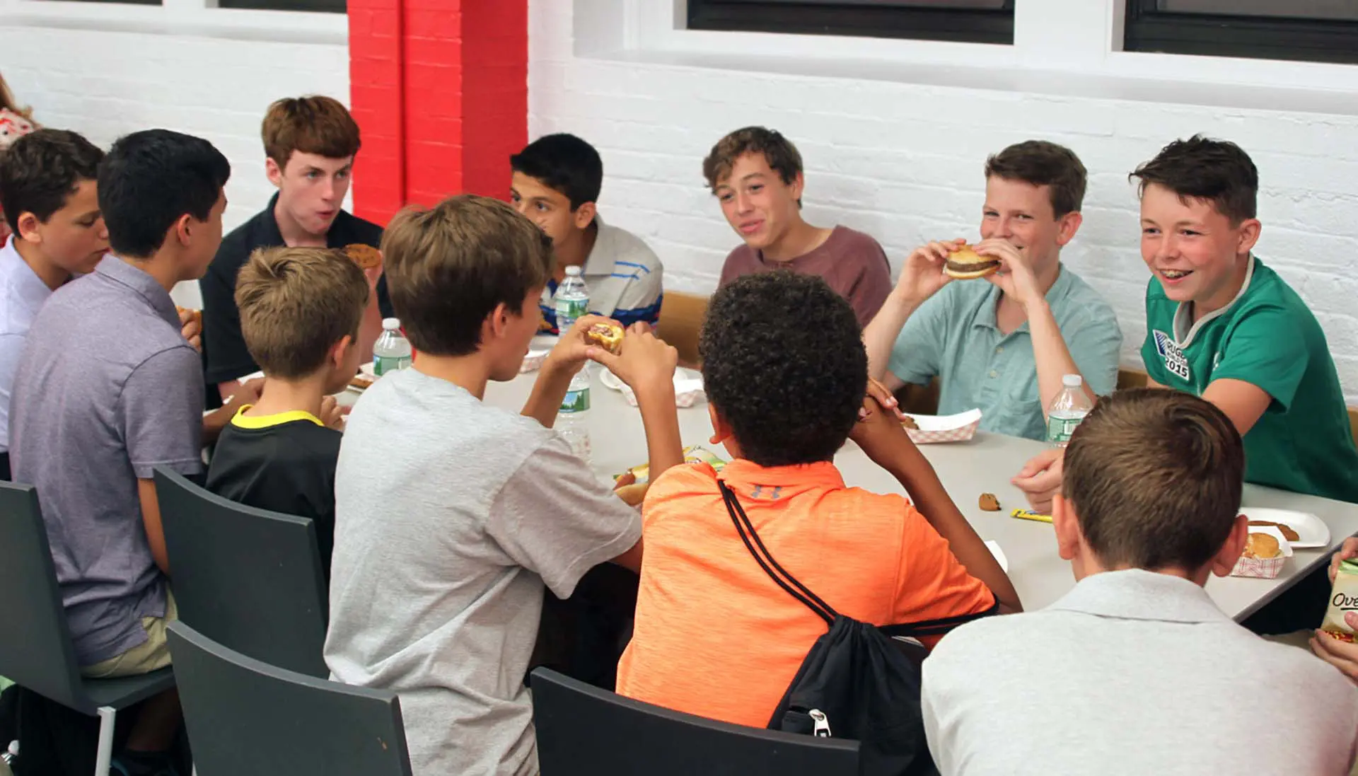 Students sitting at cafeteria table enjoying lunch