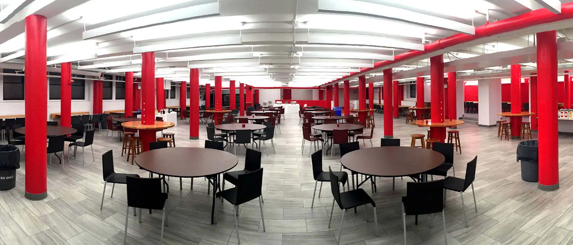 wide shot of cafeteria dining area with tables, chairs and red columns